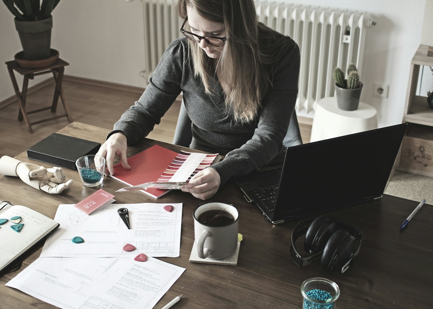 Woman reviews color swatches at a wooden desk with design documents.