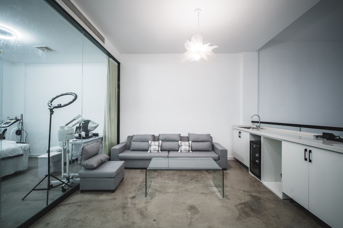 Modern waiting area with grey sofa and view of treatment room.
