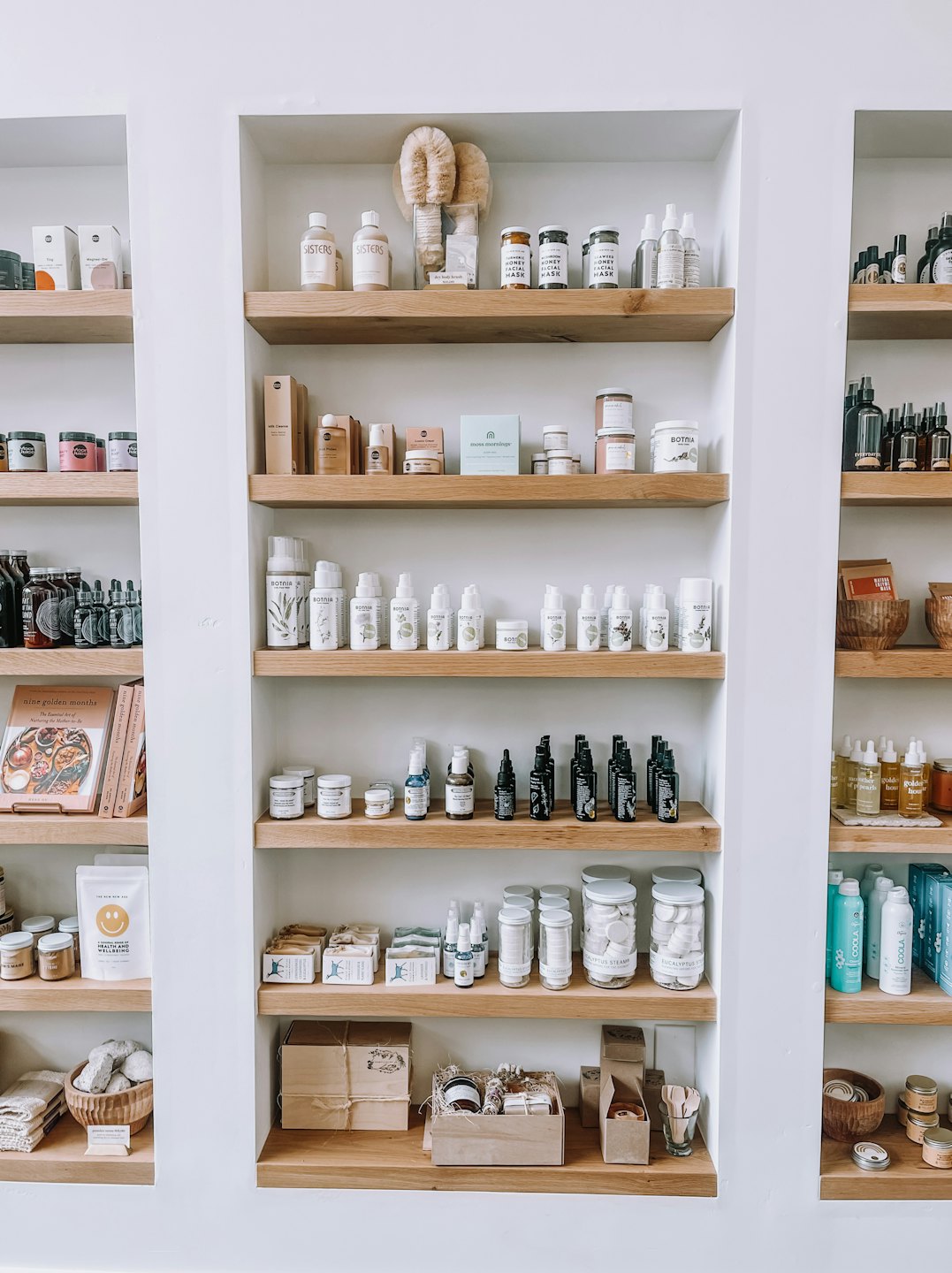 Natural beauty products displayed on wooden shelves in a store.